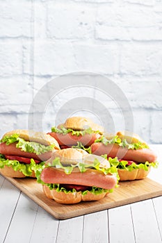 A few hot dogs on a wooden Board. Hot dog with lettuce tomato and sausage. Copy space.