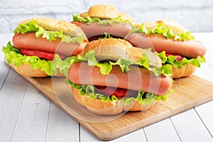 A few hot dogs on a wooden Board. Hot dog with lettuce tomato and sausage. Copy space.