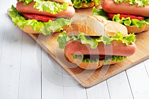 A few hot dogs on a wooden Board. Hot dog with lettuce tomato and sausage. Copy space