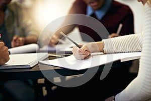 Only a few last minute changes. Shot of a group of unrecognizable people making notes on paper while being seated around