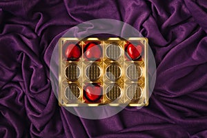 A few left red hearts in the golden box againts elegant purple satin or silk wave background. Looks like a healthy pills box