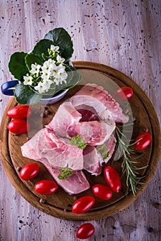 Few long slices of pork meet on chopping board with tomatoes