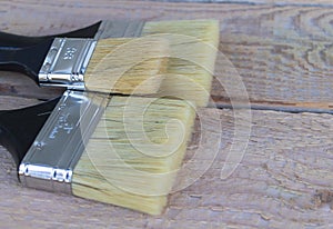 A few paintbrushes close up on a wooden background, two larger and one smaller