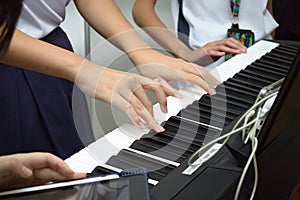 A few pairs of hands playing a musical keyboard piano organ instrument