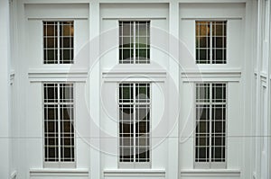 A few pieces of large window panes with grilles at a side wall of a white building