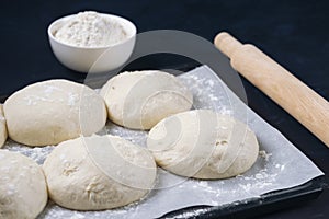 A few pieces of yeast dough in baking tray with rolling pin and flour bowl. Process of making bakery. Adjarian Khachapuri Recipe