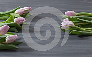 Few pink tulips flowers on dark chalcboard surface. Bouquet on a blur abstract background with copy space.