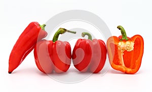 Few red ripe sweet peppers and one pepper in a cut on a light background.