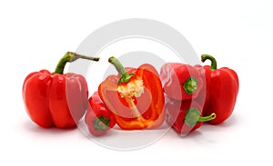 Few red ripe sweet peppers and one pepper in a cut on a light background.