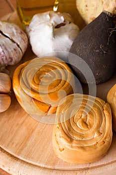 Few rolled smoked cheeses on wooden plate with vegetable