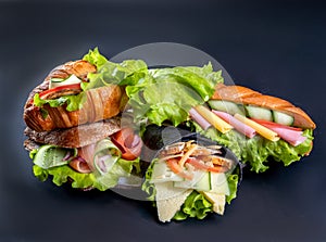A few sandwiches and rolls with cheese, salad, sausage and vegetables