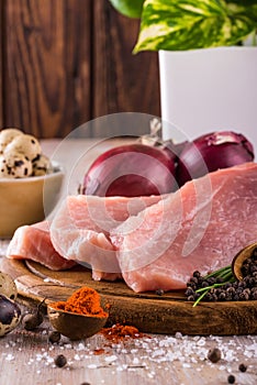 Few slices of raw pork meat on vintage wooden plate