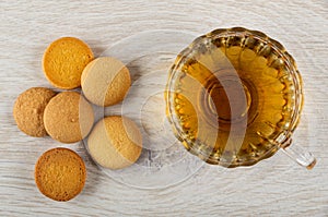 Few small biscuits, transparent cup with tea on table. Top view