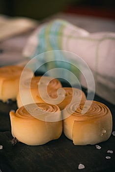 Few smoked cheese rolls on dark wooden board with spice around
