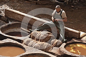 FEZ, MOROCCO - FEBRUARY 20, 2017: Man working within the paint holes at the famous Chouara Tannery in the medina of Fez.
