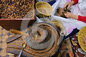 Fez, Morocco - top view of Argan oil stone handmill, box with seeds, female hands pounding nuts. Labor-intensive production.