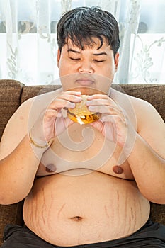 Ffat man eating hamburger seated