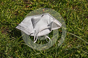 An FFP mask is thrown away in a meadow and pollutes the environment