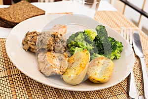 Ffried river trout fillet with a complex side dish of broccoli, baked potatoes and mushroom sauce