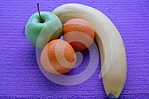 Ffruit on a lilac napkin of resh mandarins and green apple and bananas on view from above