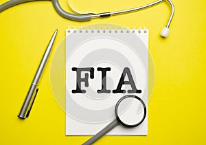 fia words on with stethoscope on notepad and yellow background