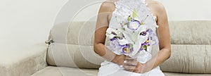 Fiancee in a beautiful white dress holding a beautiful bouquet of wedding flowers made of tender roses and lilies in hand