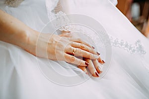 Fiancee hands with ring on the wedding dress