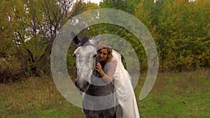 Fiancee in white dress is sitting on horse. Close up