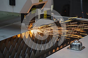 The fiber laser cutting machine cutting the sheet metal  plate with the sparkling light.