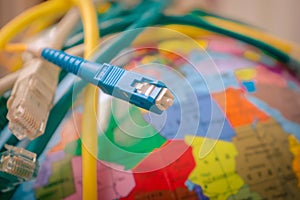 Fiber optic patch cord is close-up on a background of the globe. Different Internet wires entangle the Earth. High-speed cable.