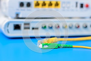 Fiber optical and network cables with internet wireless router on a blue background