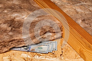 Fiberglass insulation with cash money in attic of house.