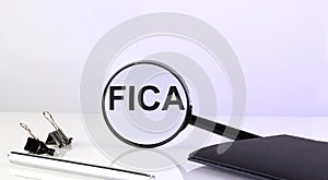 FICA concept. Magnifier glass with text with notebook and pen photo