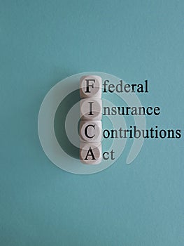 FICA symbol. Concept words FICA federal insurance contributions act on wooden cubes on beautiful blue background