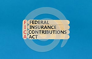 FICA symbol. Concept words FICA federal insurance contributions act on wooden stick on beautiful blue background. Business FICA