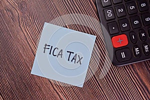 FICA Tax write on sticky notes isolated on Wooden Table photo