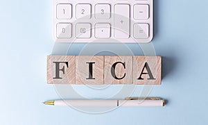 FICA on wooden cubes with pen and calculator, financial concept photo