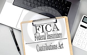 FICA word on clipboard on laptop with calculator and pen