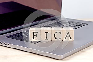 FICA word on wooden block on laptop, business concept photo