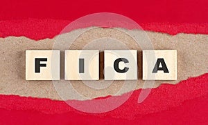 FICA word on wooden cubes on red torn paper , financial concept background