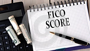FICO SCORE - words in a notebook on the background of a calculator and banknotes