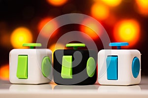 Fidget cube anti stress toy. Detail of finger play toy used for relax. Gadget placed on colorful bokeh background