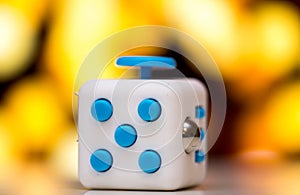 Fidget cube anti stress toy. Detail of finger play toy used for relax. Gadget placed on colorful bokeh background