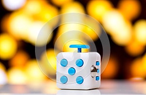 Fidget cube anti stress toy. Detail of finger play toy used for relax. Gadget placed on colorful bokeh background