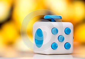 Fidget cube anti stress toy. Detail of finger play toy used for relax. Gadget placed on colorful bokeh background