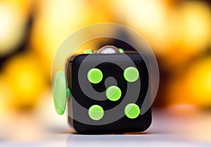 Fidget cube anti stress toy. Detail of finger play toy used for relax. Gadget placed on colorful bokeh background