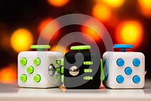 Fidget cube anti stress toy. Detail of finger play toy used for relax. Gadget placed on colorful bokeh background