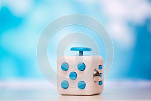 Fidget cube anti stress toy. Detail of finger play toy used for relax. Gadget placed on colorful bokeh background