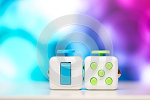 Fidget cube anti stress toy. Detail of finger play toy used for relax. Gadget placed on colorful bokeh background