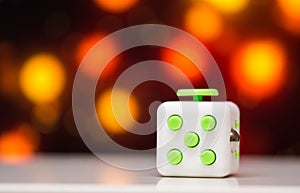 Fidget cube anti stress toy. Detail of finger play toy used for relax. Gadget placed on colorful bokeh background